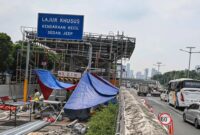 Para pekerja menyelesaikan perbaikan gerbang tol Pejompongan yang setiap hari sejak ditutup menumpukkan kendaraan di sekitarnya. (Jennus)