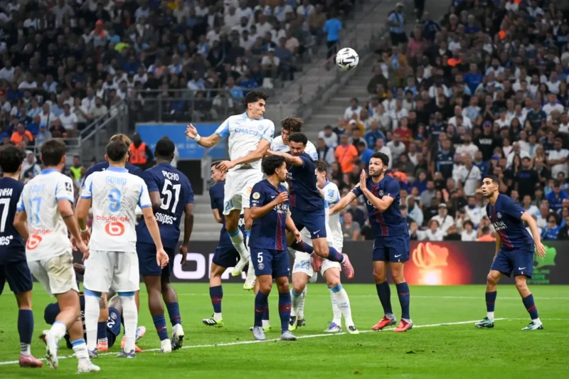 Bek Marseille Nayef Aguerd membuang bola dengan sundulan kepala dari jangkauan pemain PSG dalam pertandingan pekan kelima Liga Prancis di Stadion Velodrome, Marseille, Senin (22/9/2025) waktu setempat. (Ligue1.com)