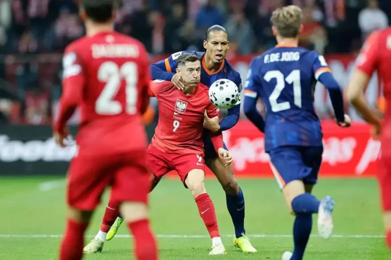 Penyerang Polandia, Robert Lewandowski dijaga ketat bek Belanda, Virgil van Dijk dalam pertandingan Kualifikasi Piala Dunia 2026 zona Eropa di National Stadium Warsaw pada Sabtu (15/11/2025). (UEFA.com)