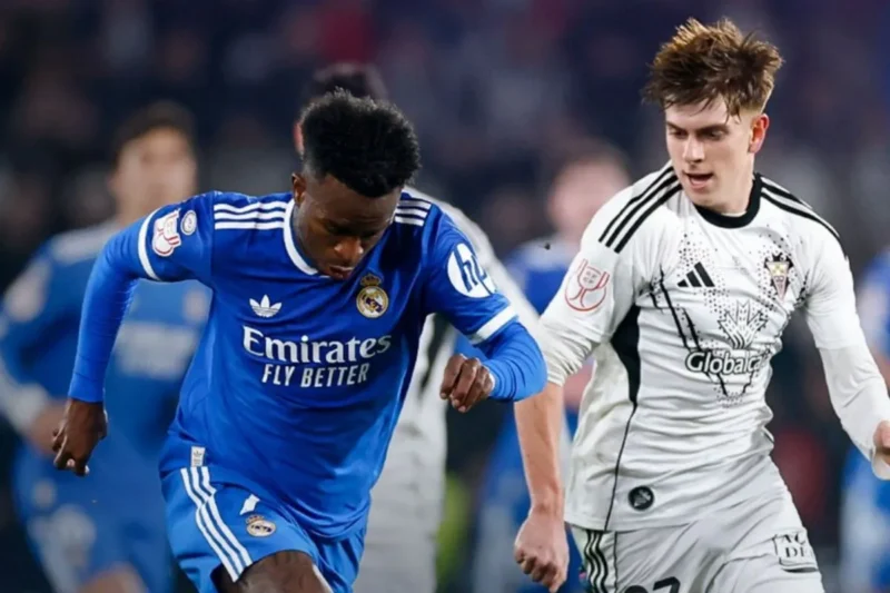 Penyerang Real Madrid Vinicius Junior (kiri) menjauhkan bola dari sergapan bek sayap Albacete Dani Bernabeu dalam laga 16 besar Piala Raja di Stadion Carlos Belmonte, Albacete, Rabu (14/1/2026) waktu setempat. (x.com/realmadriden)