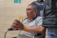 Terduga bandar narkoba Koko Erwin dengan tangan terikat cable ties duduk menunggu proses hukum selanjutnya di Bareskrim. (Istimewa)