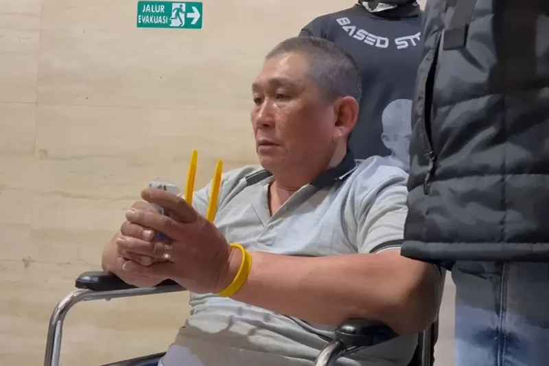 Terduga bandar narkoba Koko Erwin dengan tangan terikat cable ties duduk menunggu proses hukum selanjutnya di Bareskrim. (Istimewa)