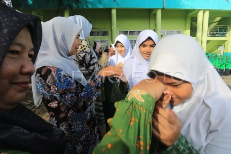 Guru di Madrasah Ibtidaiyah Negeri (MIN) 11 Aceh Barat, Aceh, menyambut siswa masuk hari pertama sekolah, Rabu (9/4/2025). (Antara Foto)