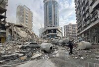 Seorang warga berjalan sendiri di atas tumpukan puing gedung yang hancur oleh serangan Israel di Beirut Selatan. (XInhua)