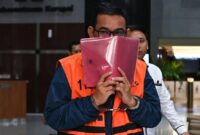 Tersangka kasus dugaan suap importasi di Direktorat Jenderal Bea dan Cukai Orlando Hamonangan menutupi wajahnya usai menjalani pemeriksaan di Gedung Merah Putih KPK, Jakarta, Senin (27/4/2026). (Indrianto Eko Suwarso/Antara Foto)