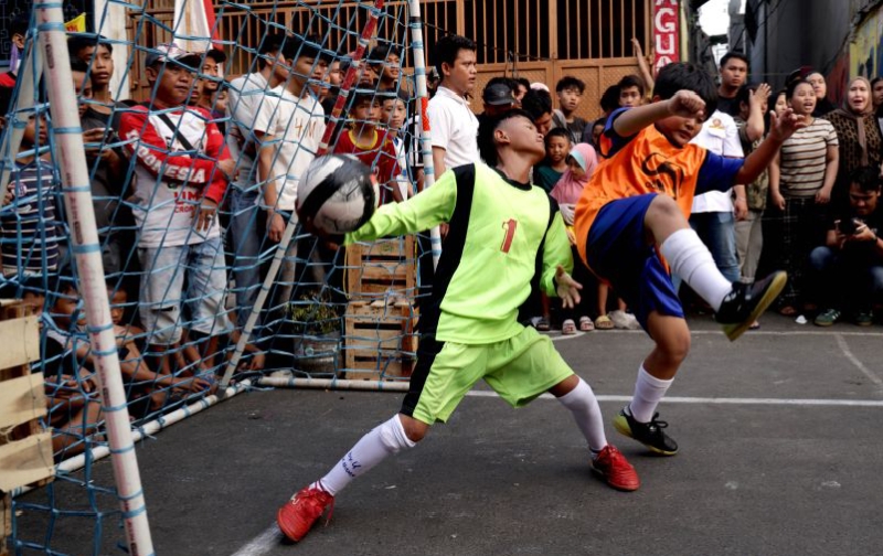 Foto yang diambil Kantor Berita Xinhua pada 21 Juni 2026, memperlihatkan keseruan pertandingan antardua kesebelasan anak-anak dalam turnamen sepak bola di ruang publik di Jalan Sawah Lio, Kecamatan Tambora, Jakarta. (Jennus)
