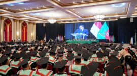 Kepala Badan Ekonomi Kreatif menyampaikan orasi ilmiah yang ditayangkan melalui layar besar di hadapan ratusan wisudawan  