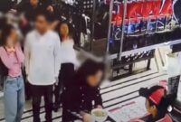 Tangkapan layar video viral di medsos, seorang wanita (berdiri mengantre paling kanan) ditendang pria berbaju hitam yang duduk di belakangnya. 