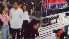 Tangkapan layar video viral di medsos, seorang wanita (berdiri mengantre paling kanan) ditendang pria berbaju hitam yang duduk di belakangnya. 