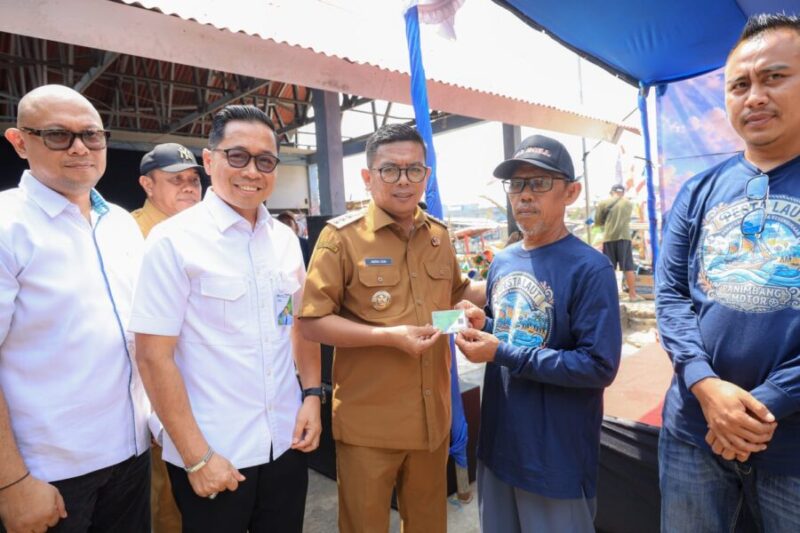 Andra Soni secara simbolis menyerahkan Kartu Kusuka/Asuransi Nelayan kepada warga dalam kunjungan kerja di Kecamatan Panimbang, Pandeglang
