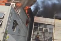 Demi menyelamatkan anaknya yang masih kecil, seorang ibu menerobos kobaran api dan membawa sang anak keluar melalui bangunan di sebelah rumah makan yang terbakar. (Tangkapan layar video amatir)