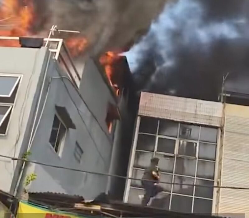 Demi menyelamatkan anaknya yang masih kecil, seorang ibu menerobos kobaran api dan membawa sang anak keluar melalui bangunan di sebelah rumah makan yang terbakar. (Tangkapan layar video amatir)